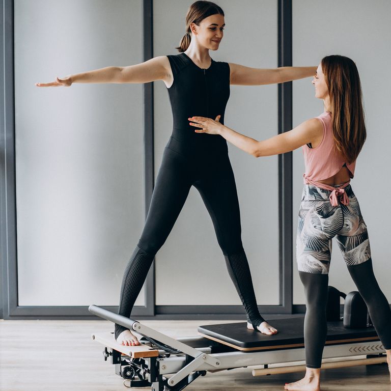 Pilates instructor guiding a client on a reformer
