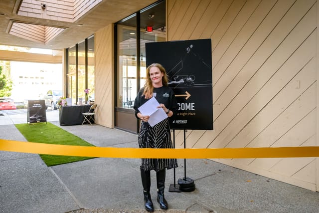 Sarah, notes in hand behind the gold ribbon just before the ribbon cutting