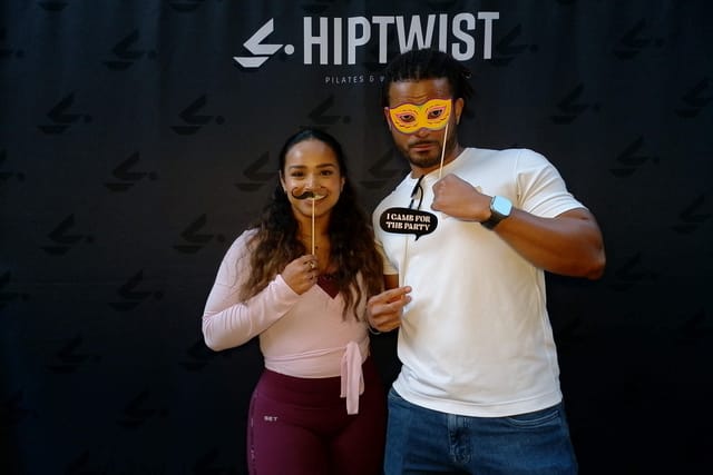 A couple posing with a mask and a party sign