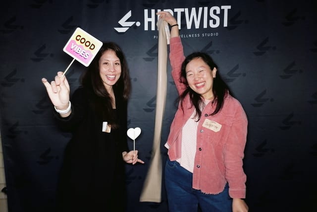 Two guests posing with a resistance band and a &ldquo;Good Vibes&rdquo; sign