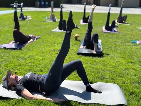 Outdoor mat Pilates class with Sarah leading bridge work at South Hillsborough Elementary